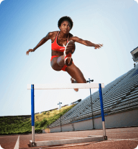 donkere vrouw is op de atletiek baan en sprint over een horde