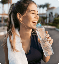 jonge vrouw in de buitenlucht die geniet van de zon met een fles water