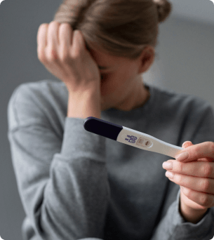vrouw houdt zwangerschapstest vast maar kijkt weg