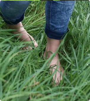 Foto van iemand zijn blootte voeten die door het gras heen loopt