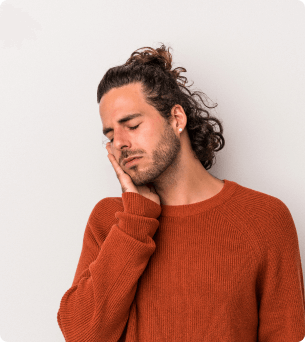 foto van een man met lang haar die met zijn hand op zijn gezicht zit