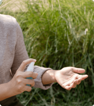 vrouw sprayt op haar onderarm iets tegen een tekenbeet