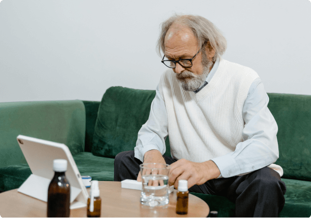 Man zit op de bank voor zijn tablet en neemt medicatie